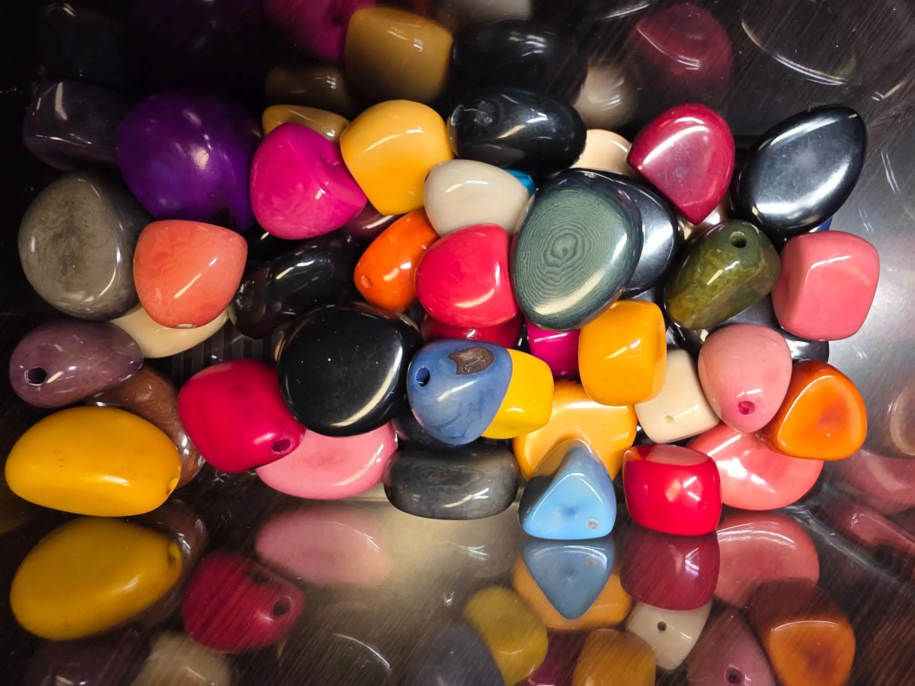 A vibrant collection of smooth polished river stones in assorted colors illustrating care for tagua vegetable ivory jewelry