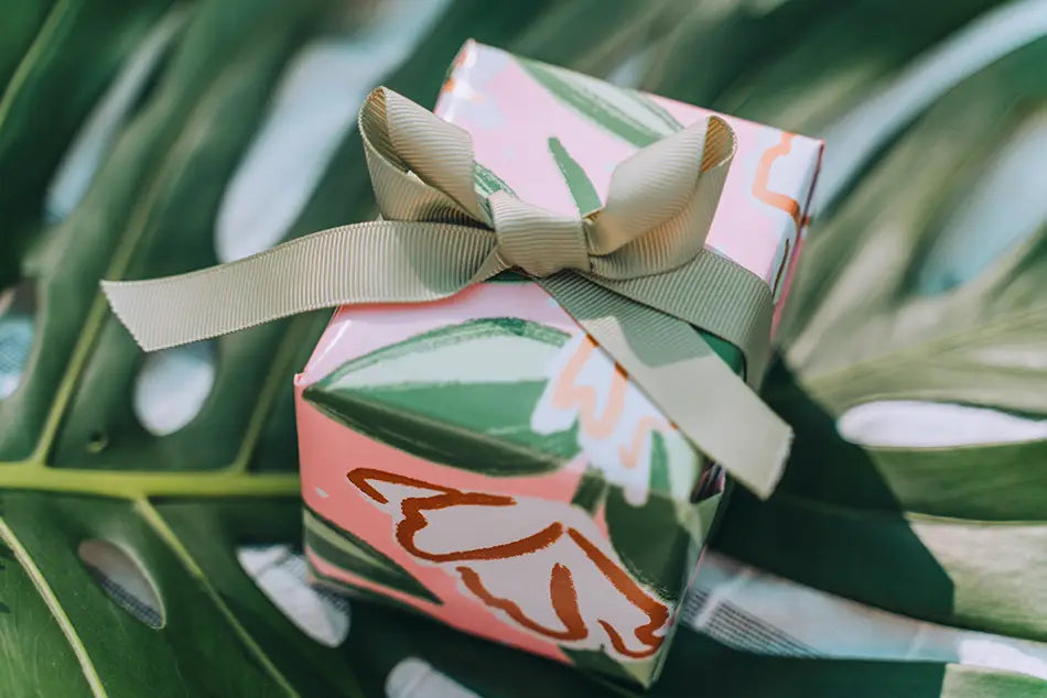 A pink and green patterned gift box with a beige ribbon bow featured in rainforest gifts article.