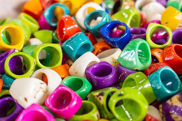 A vibrant collection of colorful glossy ceramic carved rings in various shapes and sizes