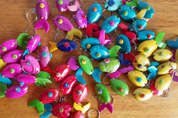 A collection of colorful plastic fish-shaped keychains in pink blue green and yellow from rainforest friends specialty animal keychains