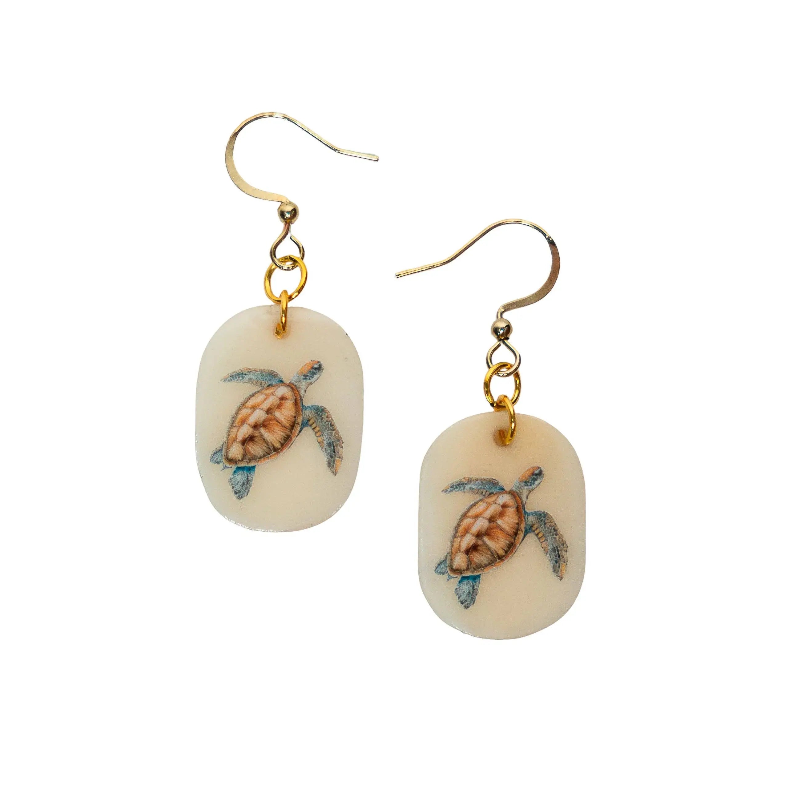 Cream-colored oval earrings with hand-painted sea turtles and gold-toned hooks from tagua plus motif designs