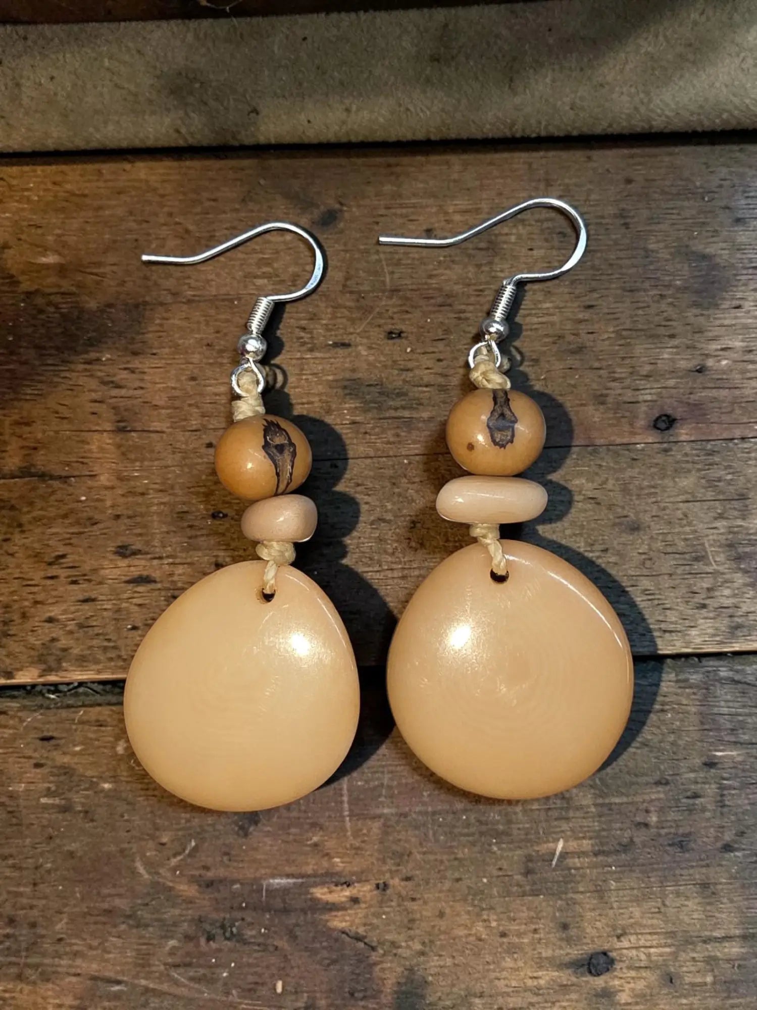 Beige teardrop-shaped bone earrings with silver hooks and bead accents from the earth and element collection