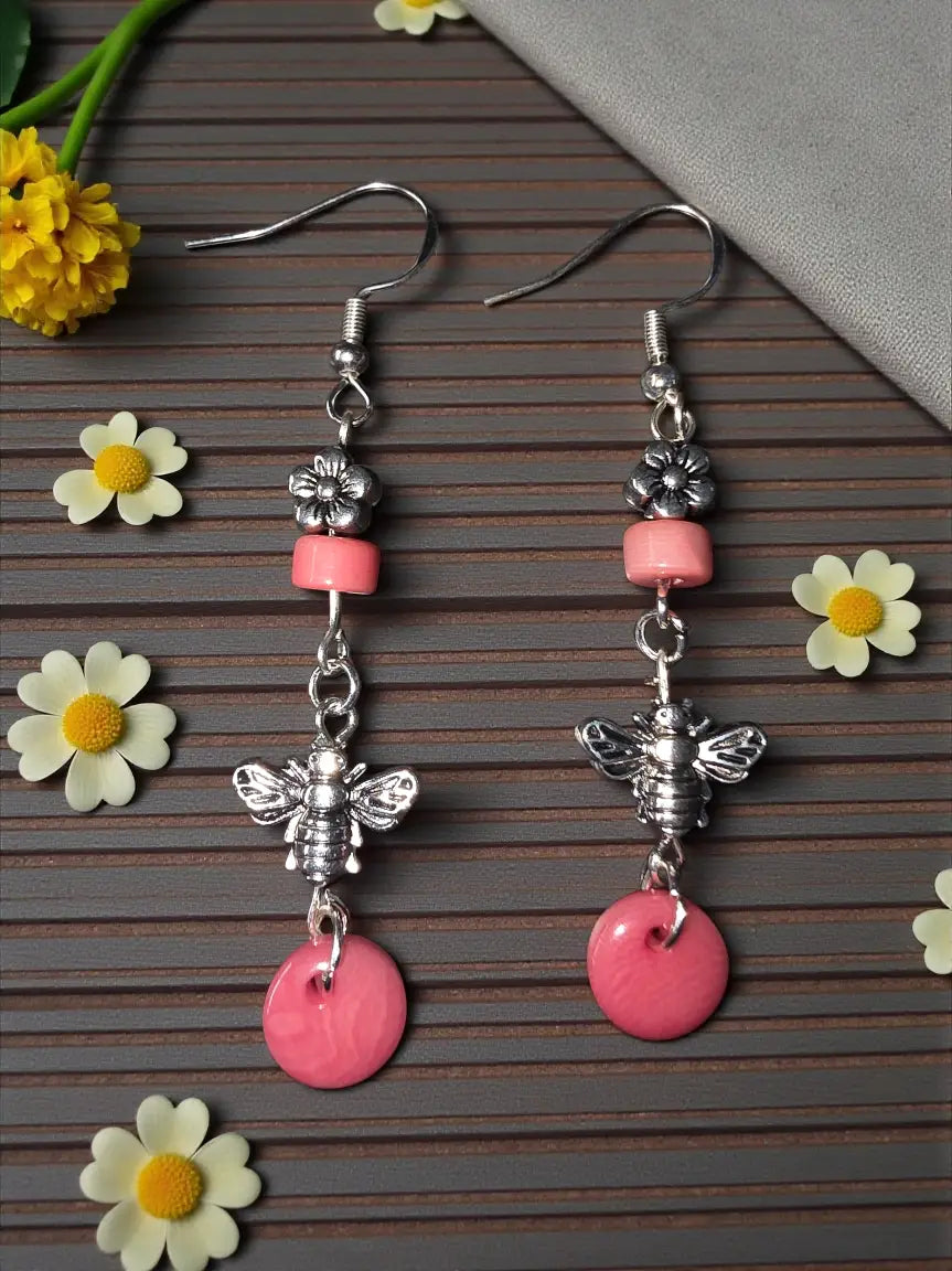 Pink and silver bee-themed drop earrings featuring pink tagua nut and flower bead accent