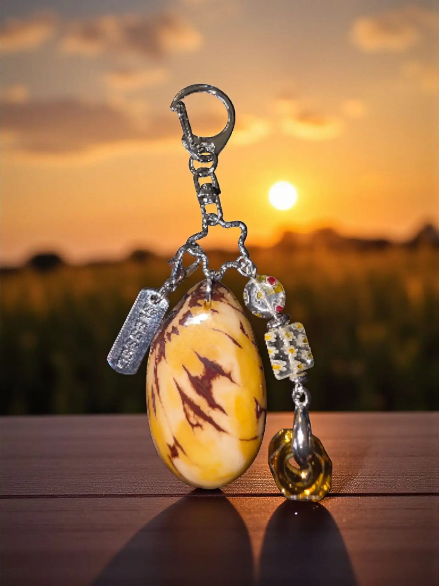 Polished yellow and brown marbled tagua egg-shaped bag charm with silver clasp and glass bead accents for purses and backpacks