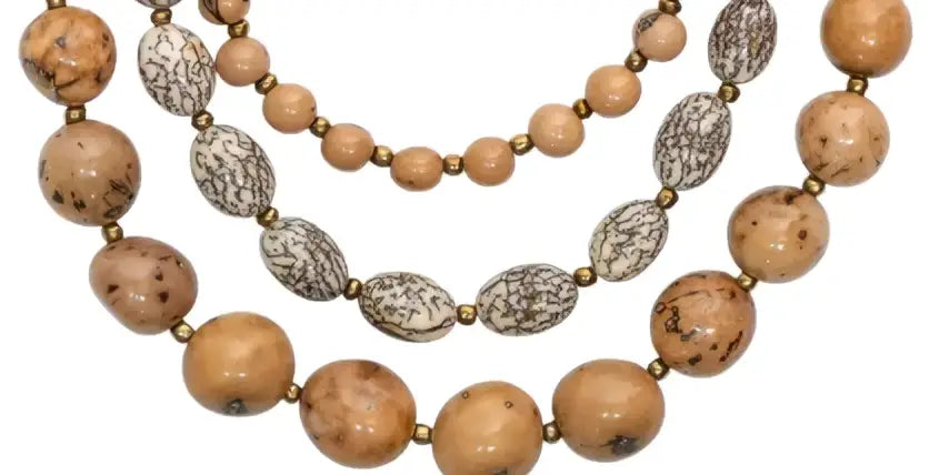 A 3-strand idra necklace with tan acai berries, tagua nut beads, and silver-toned oval metallic plates