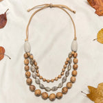 A layered 3-strand idra necklace with tan bombona seeds acai berries and tagua nut beads on beige suede cord