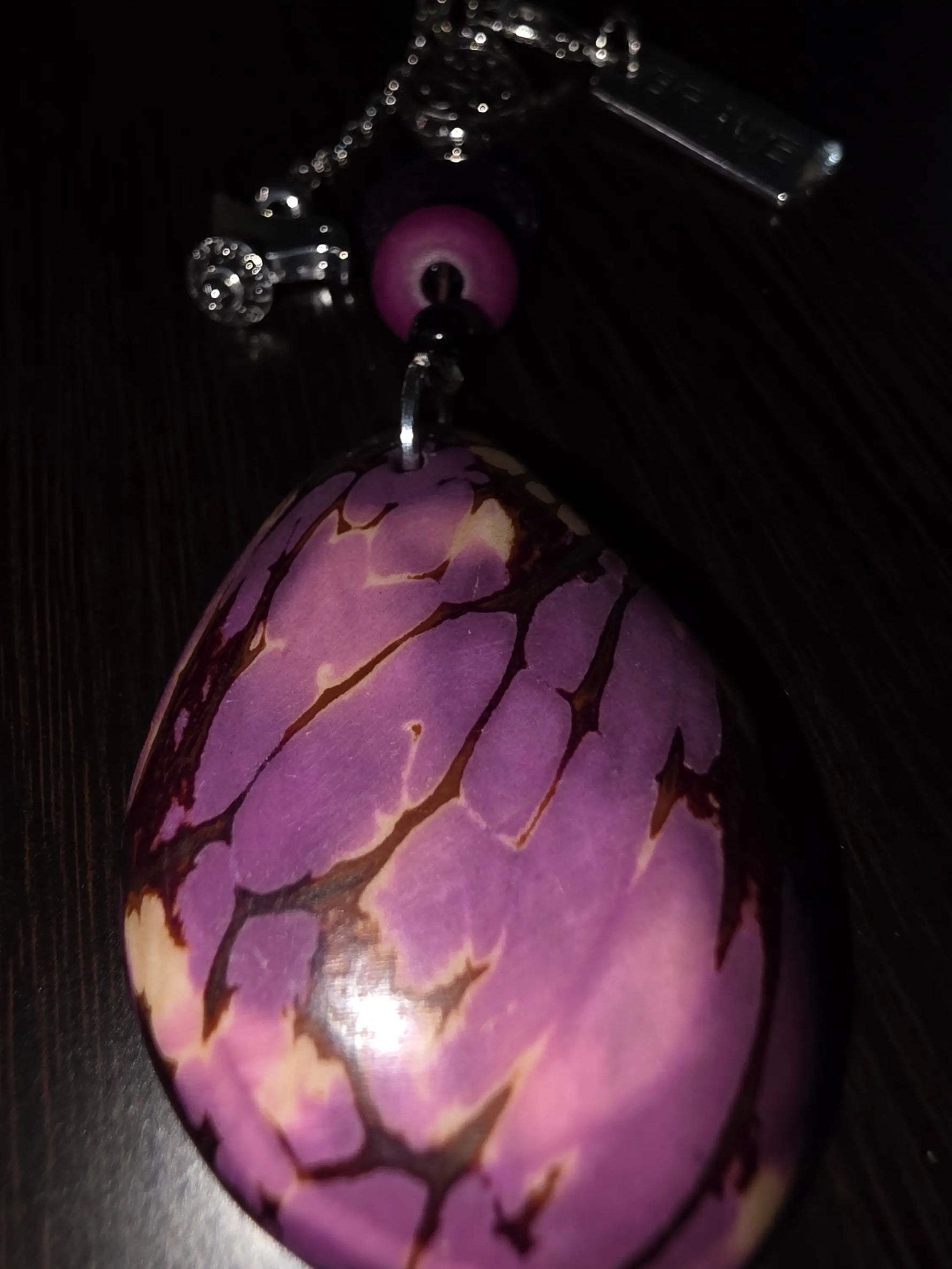 Glossy purple natural carved tagua bag charm with brave charm bird amulet bead and silver chain attachment