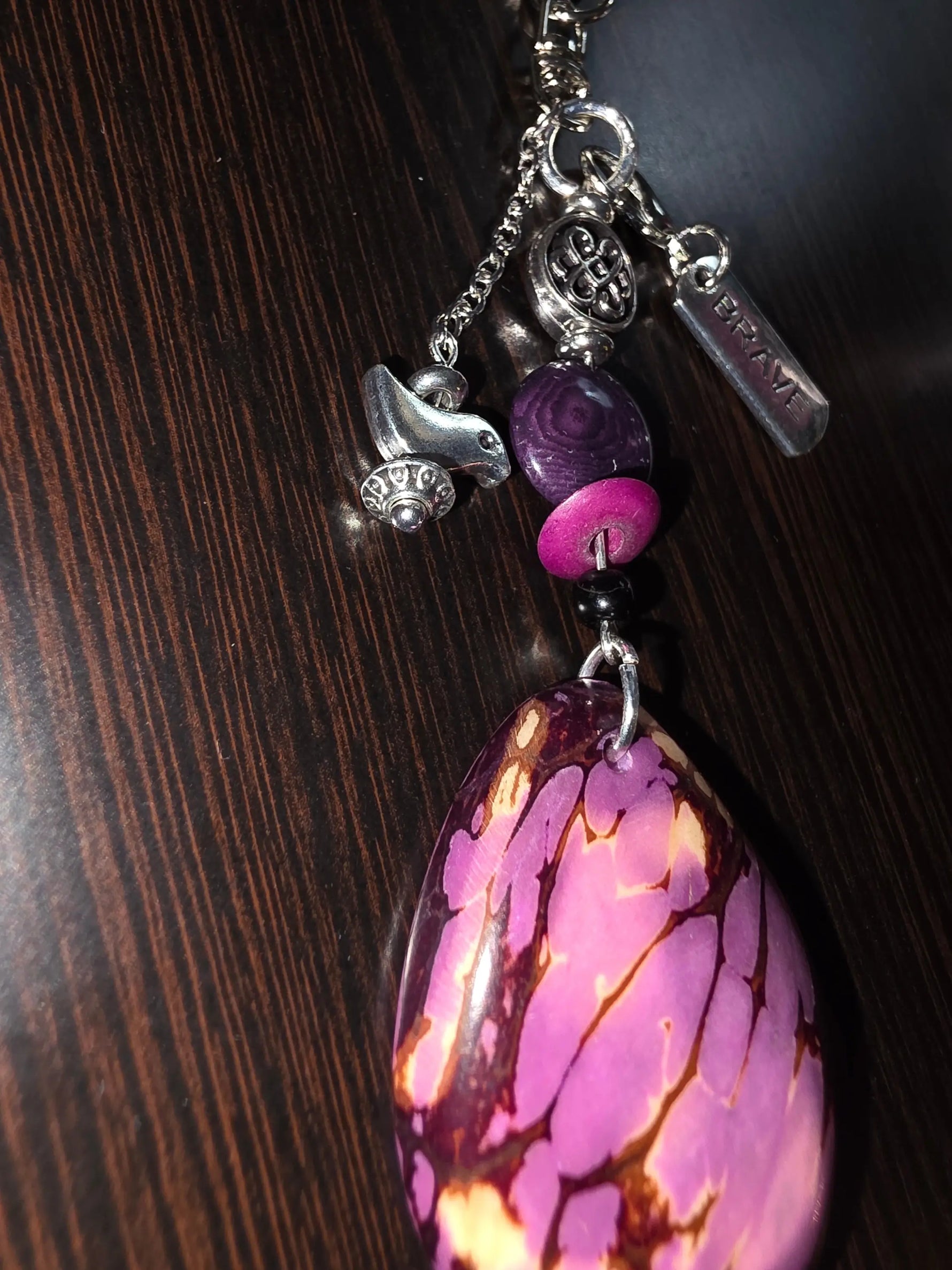 Vibrant purple natural carved teardrop bag charm with brave charm bird amulet beads and silver accents on chain