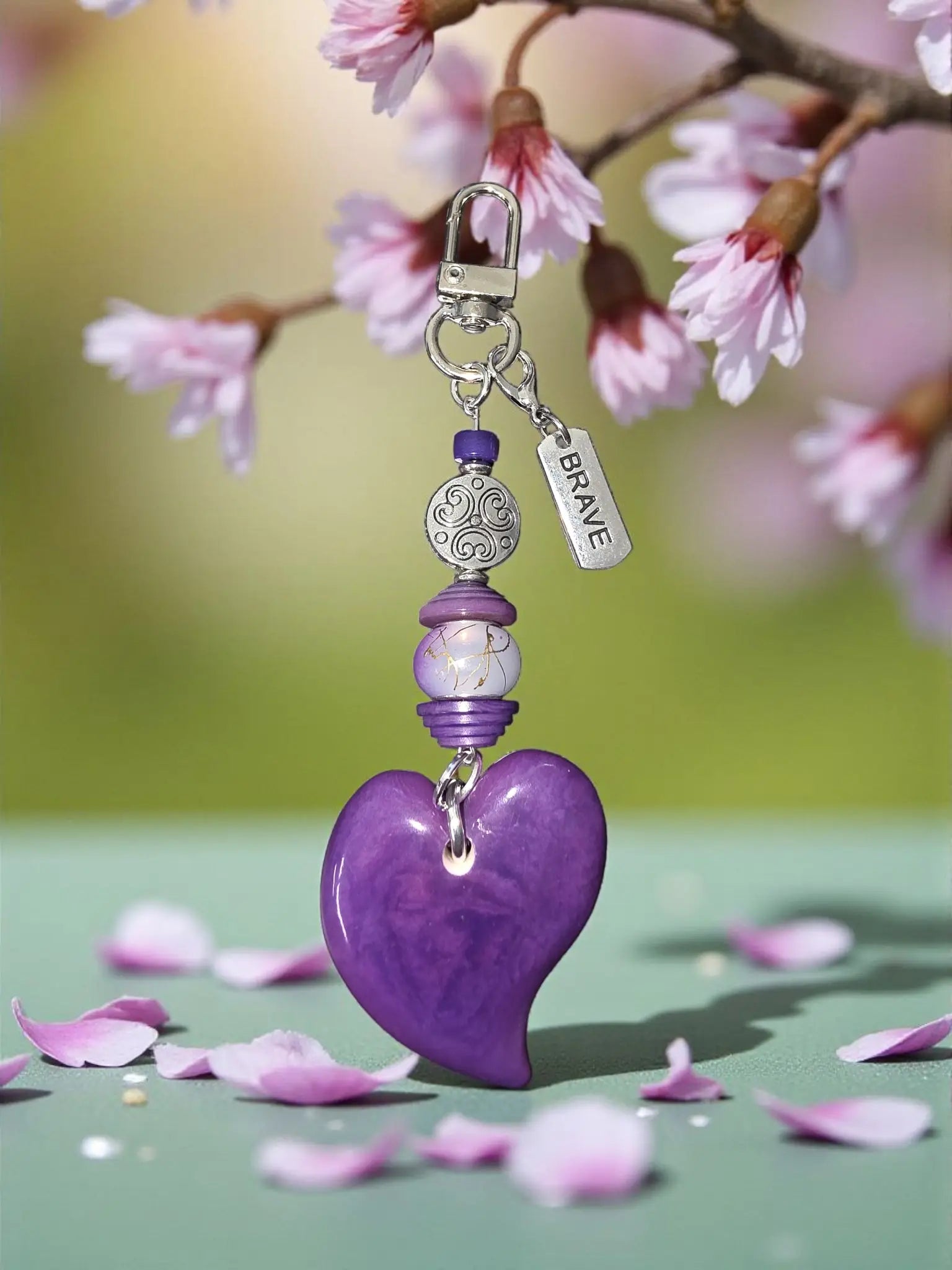 A glossy purple tagua carved heart bag charm with silver clasp and brave engraved Tibetan amulet bead