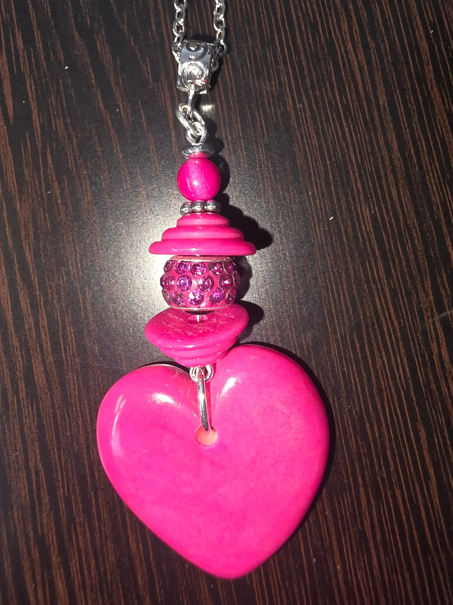 A vibrant candy hot pink thick carved heart tagua pendant necklace with silver chain and decorative beads with bling