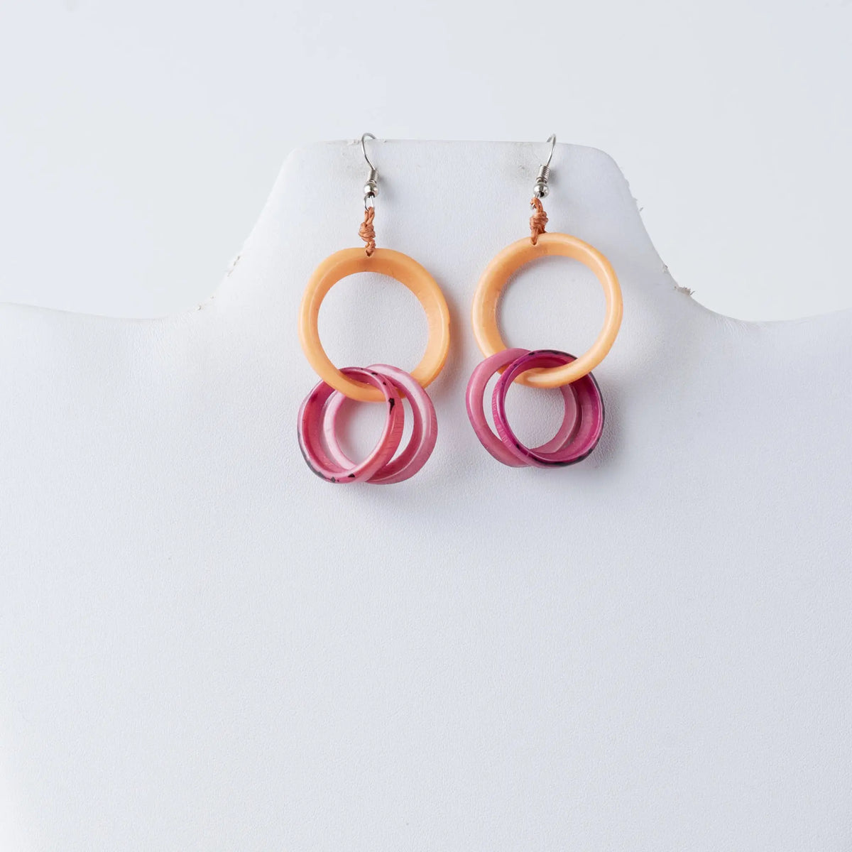 A pair of catalina circular tagua earrings with layered peach and translucent pink hoop rings with gradient shading