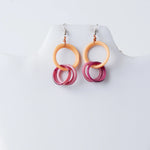 A pair of catalina circular tagua earrings with layered peach and translucent pink hoop rings with gradient shading