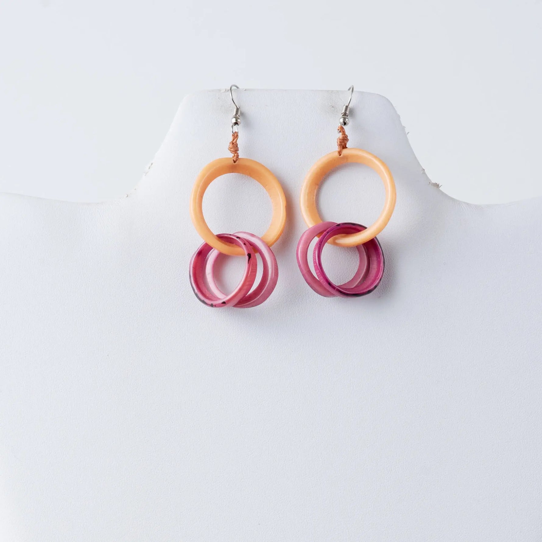 A pair of catalina circular tagua earrings with layered peach and translucent pink hoop rings with gradient shading