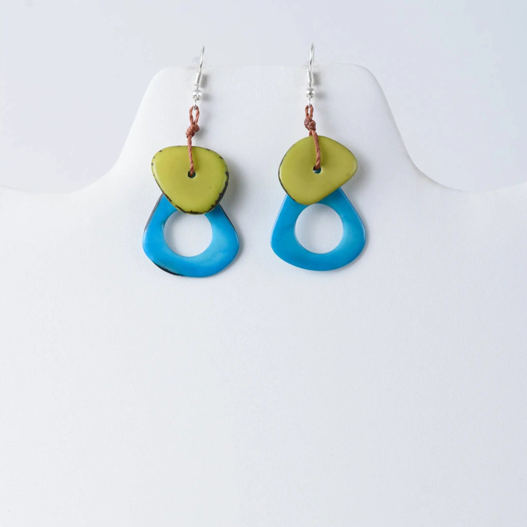 A pair of charli geometric tagua earrings with lime green discs and translucent blue teardrop drops in vibrant tones