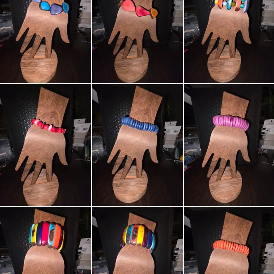 Colorful, handcrafted beaded bracelets displayed on wooden hand-shaped stands.
