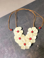 Cream ivory carved tagua chips flower bib necklace with layered petals red bead centers and tan cord slider by becca
