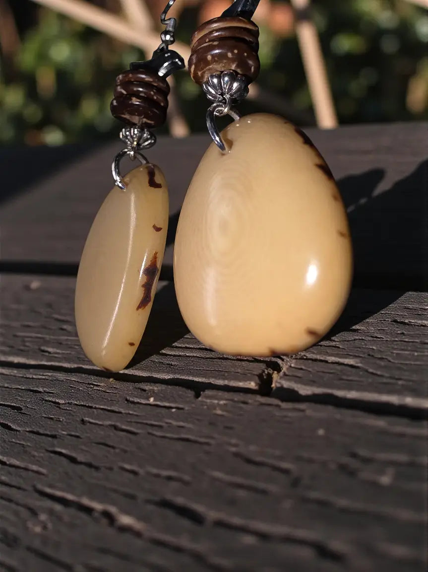 Cream sliced tagua nut earrings with amber bird bead accents and silver clasps featuring dark brown inclusions