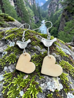 Silver bird-shaped earrings with spiral details and light beige carved vegetable ivory heart pendants from the rainforest