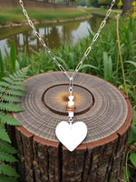 Silver chain pendant necklace featuring a cream white carved heart lightweight tagua with copper-toned accents