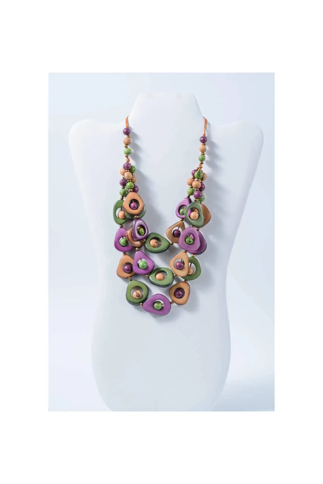 A vibrant eden three stranded tagua necklace with purple green and tan beads and metallic accents