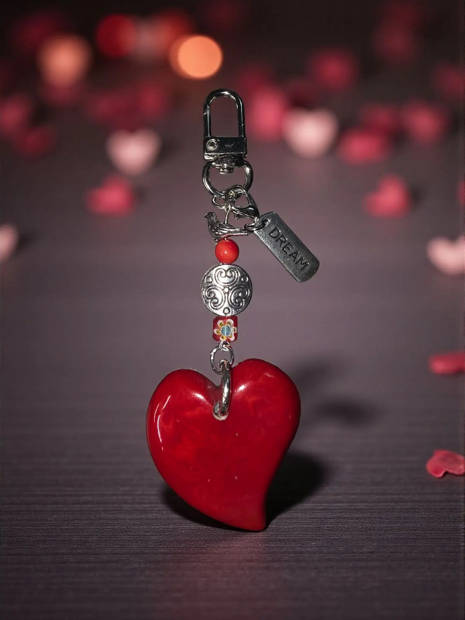 A glossy red tagua carved heart bag charm with silver-toned clasp and Tibetan amulet metal bead
