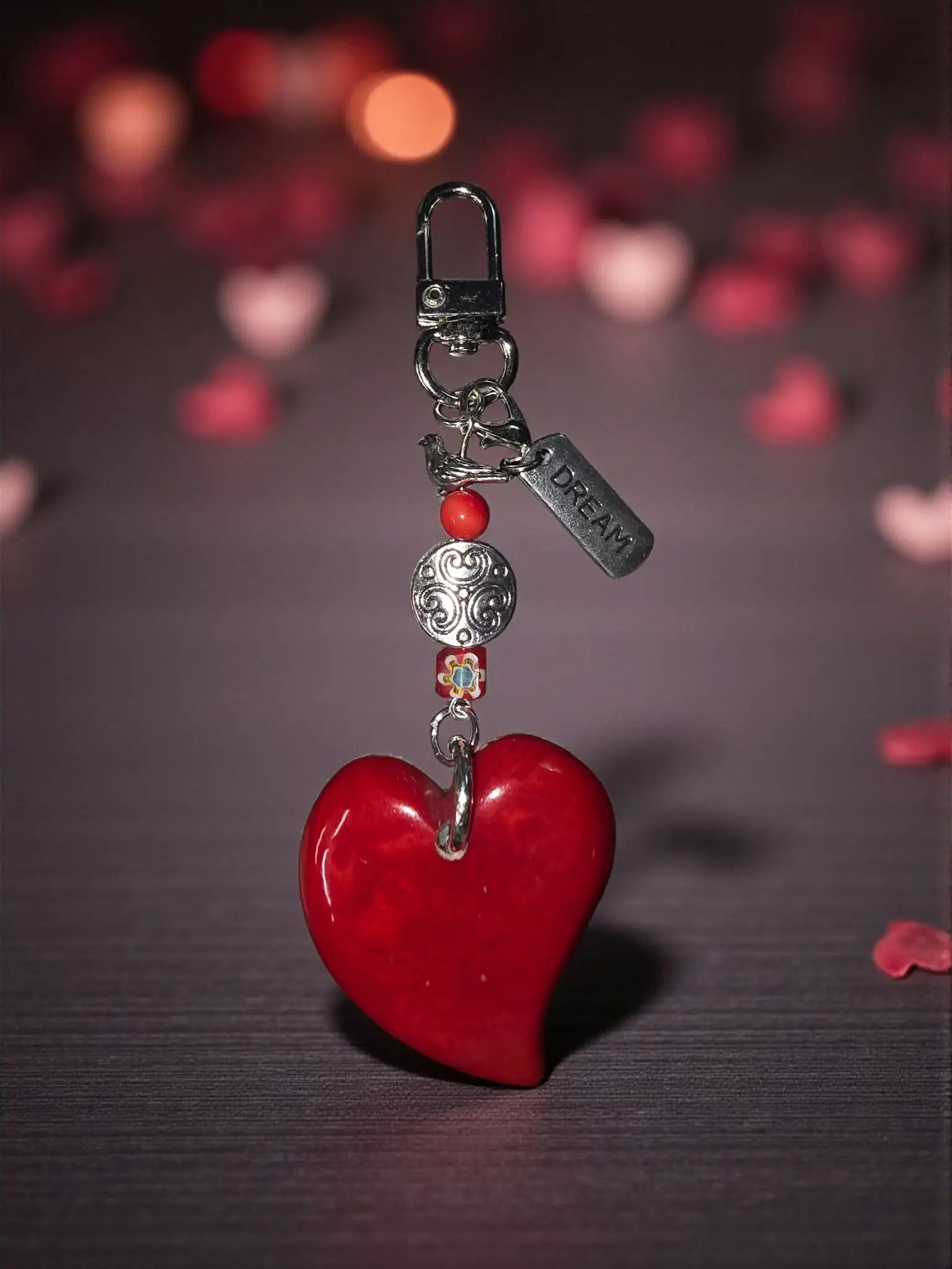 A glossy red tagua carved heart bag charm with silver-toned clasp and Tibetan amulet metal bead