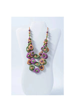 A vibrant eden three stranded tagua necklace with irregular purple green and tan beads and metallic accents