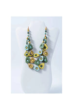 A vibrant eden three stranded tagua necklace with green and yellow teardrop beads and a circular center accent