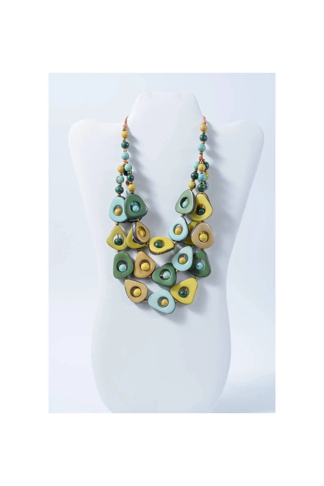 A vibrant eden three stranded tagua necklace with green and yellow teardrop beads and a circular center accent