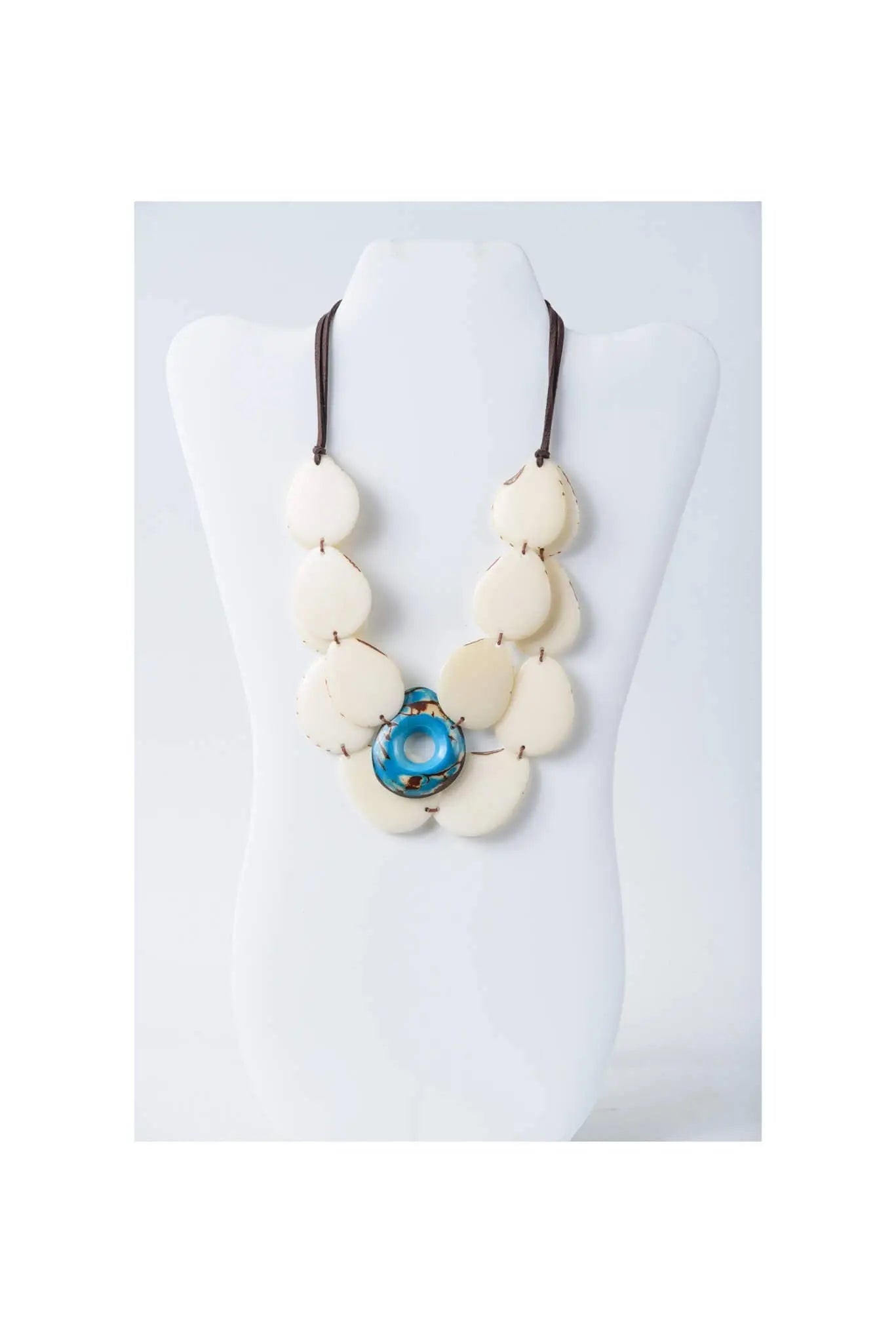 Cream-colored oval beads layered tagua slice necklace with blue pendant on adjustable dark brown cord