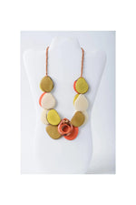 A vibrant ella layered tagua slice necklace with yellow cream and orange teardrop pendants on a braided copper chain