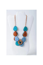 Ella layered tagua slice necklace with vibrant blue pink and brown teardrop beads and a pink patterned center ring