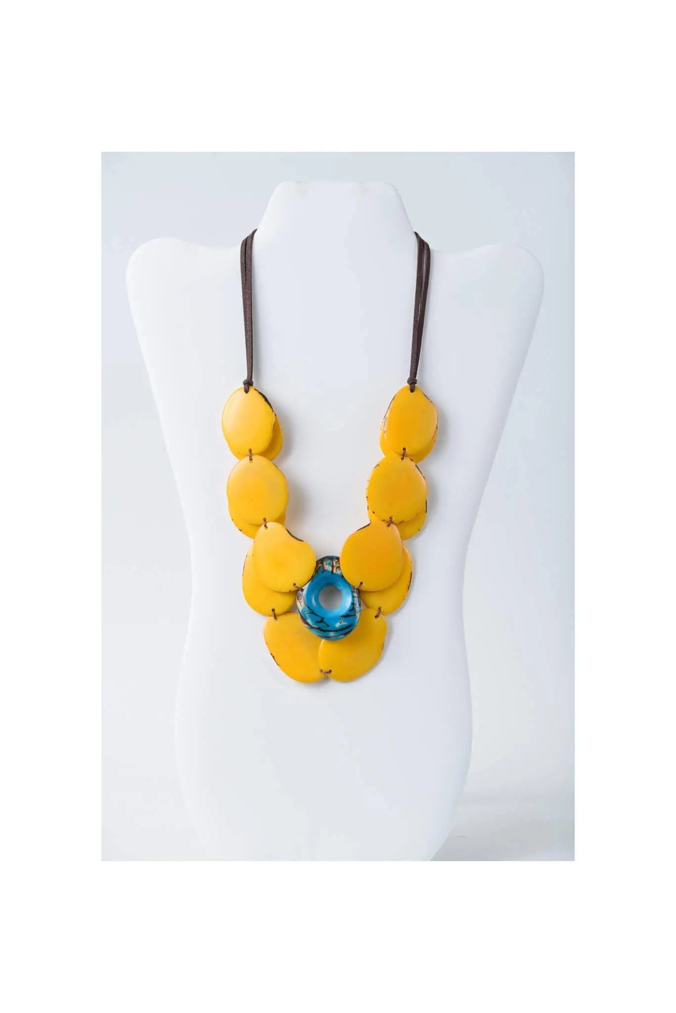 Yellow leaf-shaped resin beads and a blue glass accent on dark cord in the ella layered tagua slice necklace