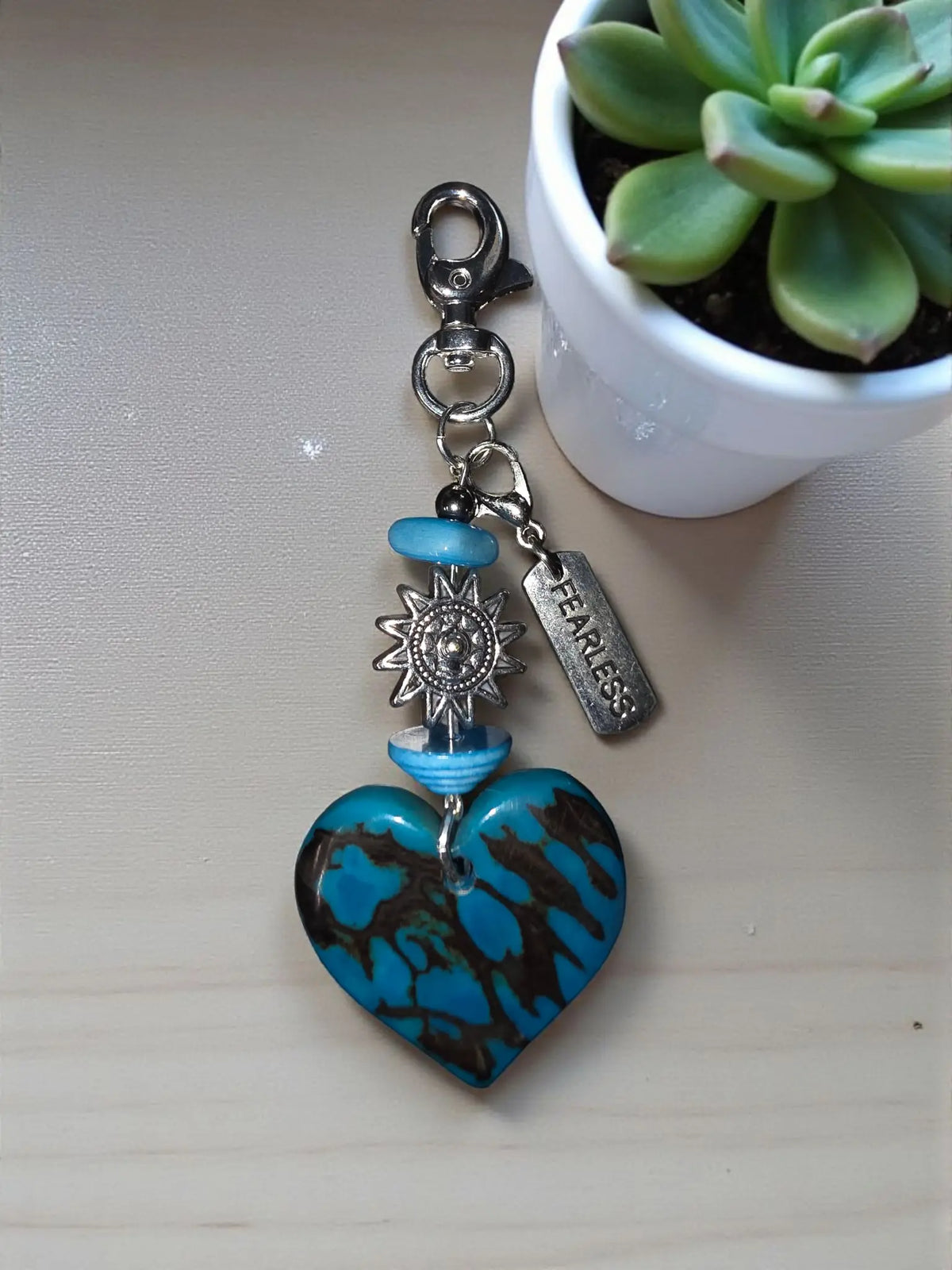 Turquoise and black marbled heart-shaped tagua keychain with silver sun charm blue beads and engraved fearless tag