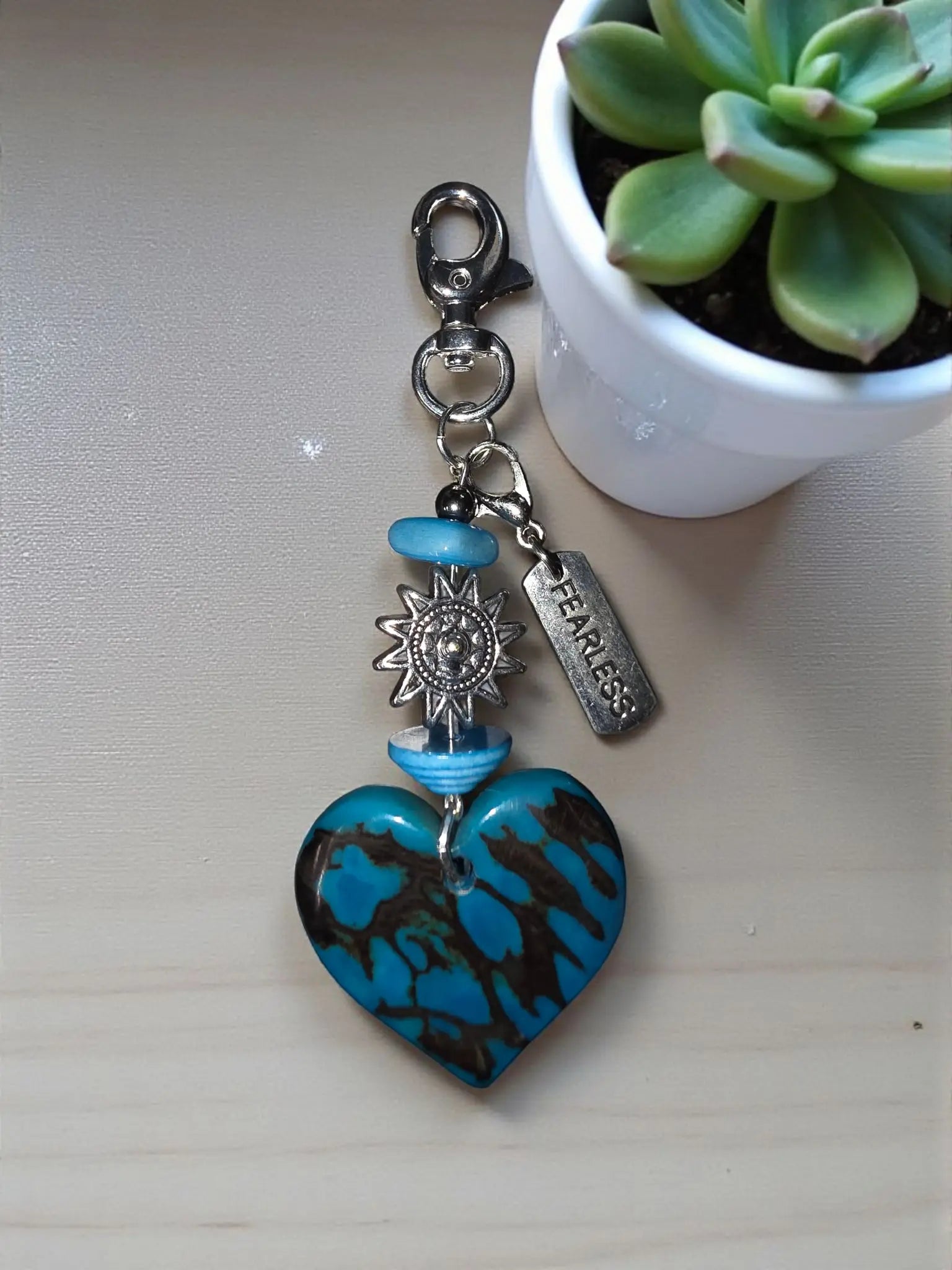 Turquoise and black marbled heart-shaped tagua keychain with silver sun charm blue beads and engraved fearless tag