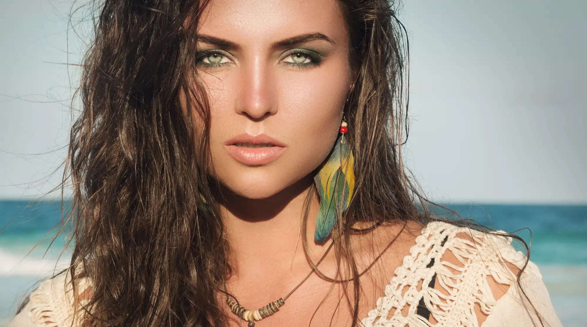 Feather earrings with green, yellow, and red hues.