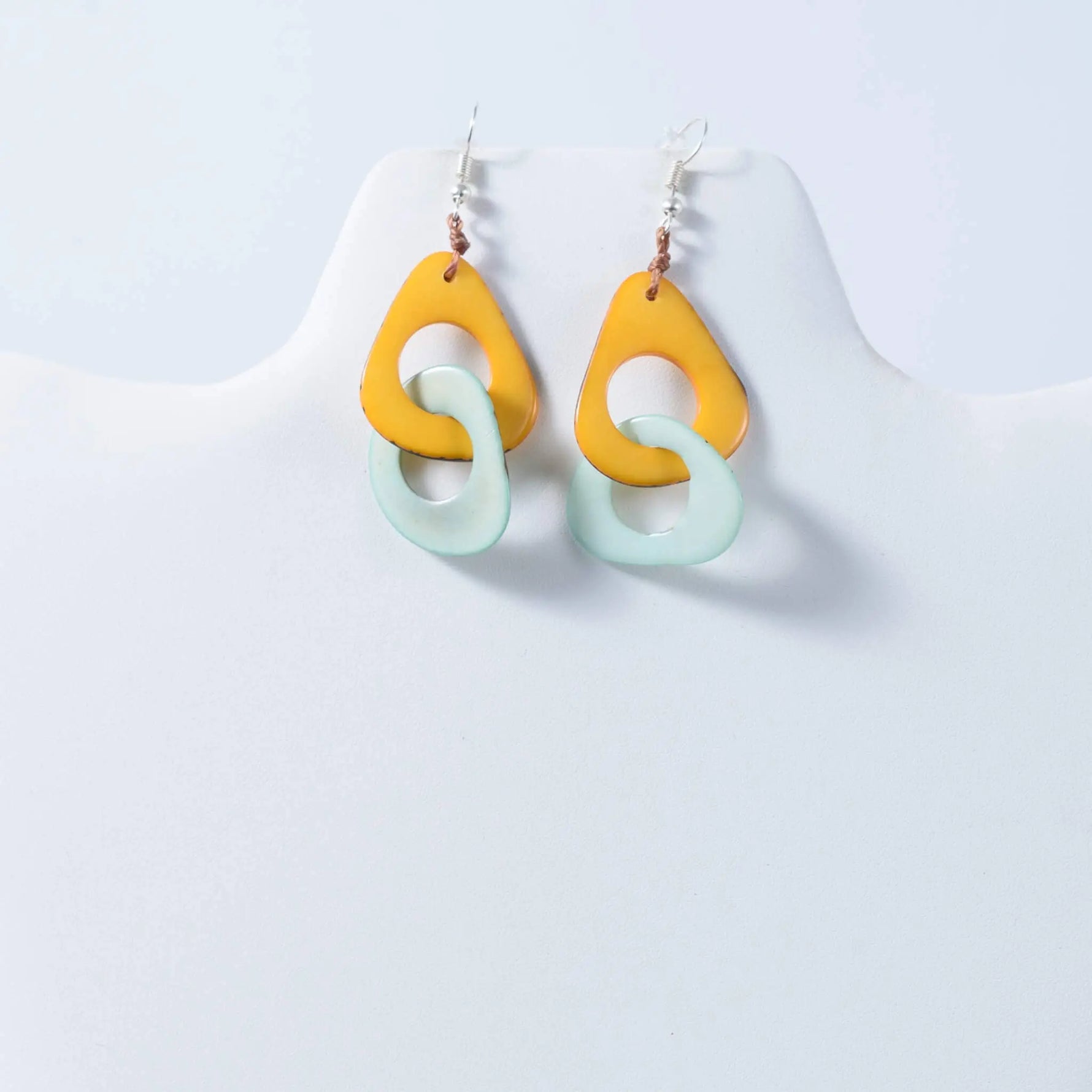 A pair of fern interlocking tagua earrings with bold yellow and soft mint green resin teardrop shapes
