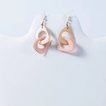 Pastel pink and beige resin drop fern interlocking tagua earrings with a modern ring design