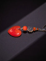 A vibrant red carved heart meets sun amulet pendant necklace with orange beads on an ornate silver-toned chain