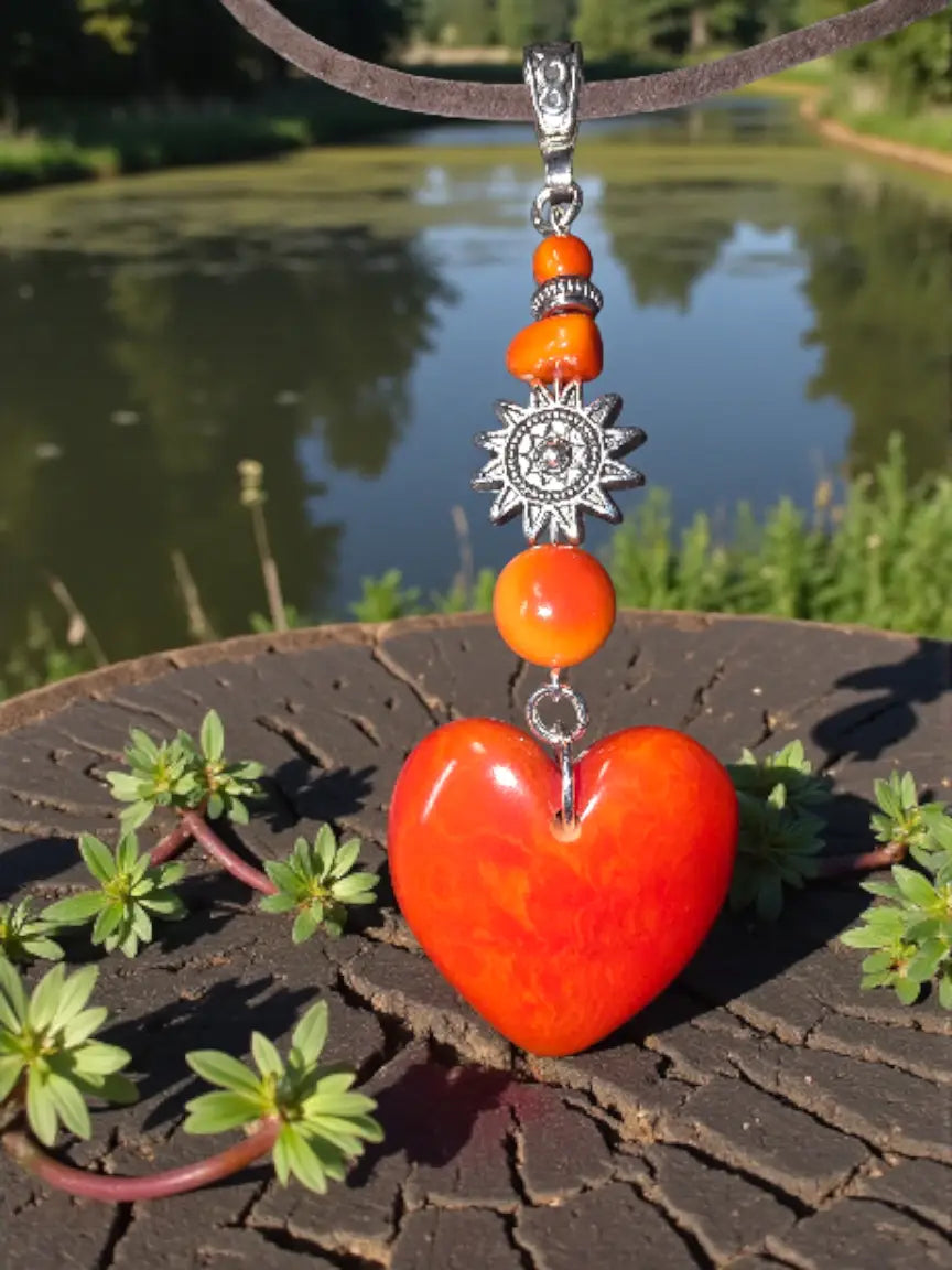 A vibrant flame orange carved heart meets sun amulet pendant necklace with glossy finish and silver-toned chain