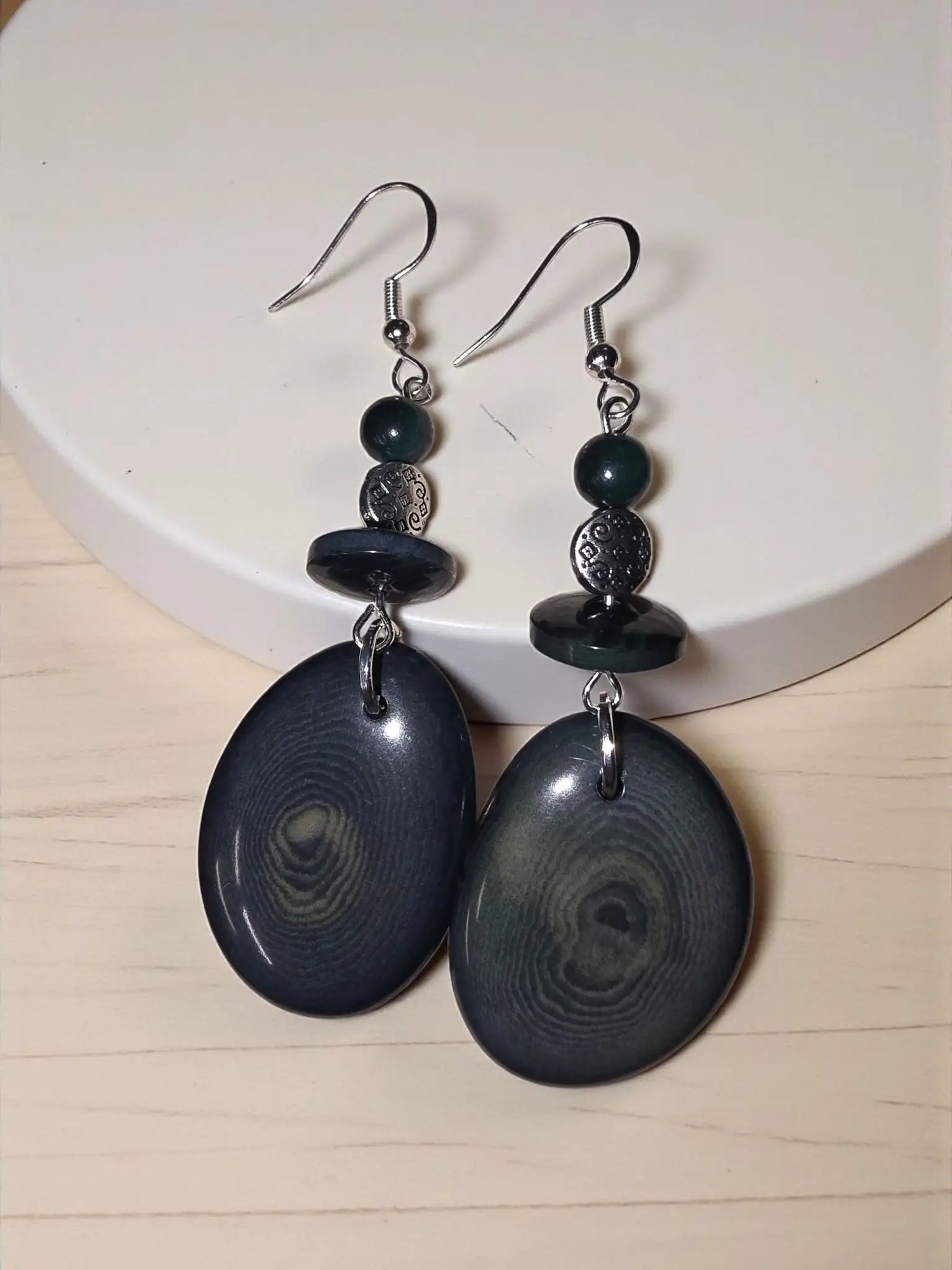 Forest green thick slice tagua earrings with dark blue oval shapes and swirling gray patterns with silver hooks