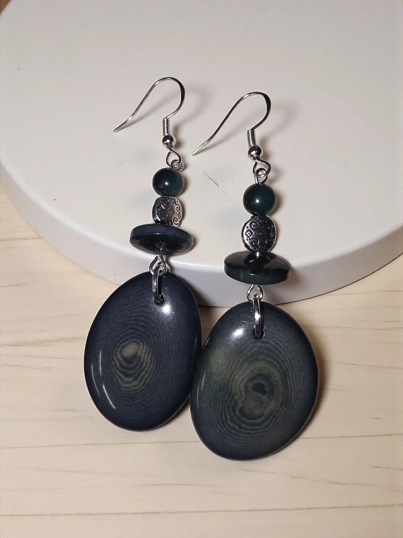 Forest green thick slice tagua earrings with dark blue oval shapes and swirling gray patterns with silver hooks