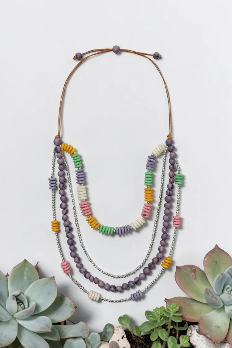Four-strand tagua nut necklace with layered purple, green, yellow, and pink antique beads on silver chain with brown cord closure