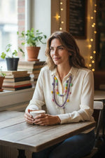 A woman wears a four-strand tagua nut sunny necklace with pastel antique beads in purple pink yellow and green