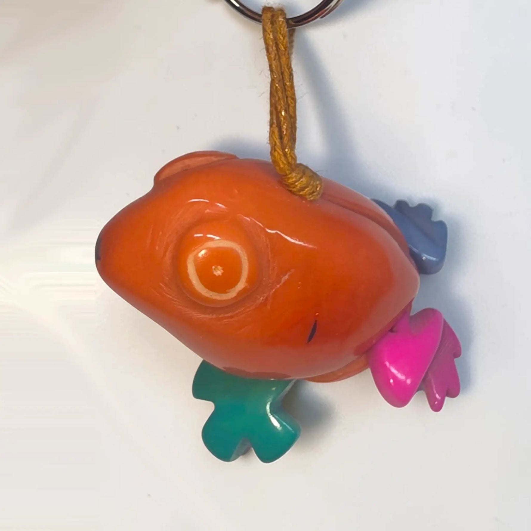 Glossy orange fish-shaped hand-carved tagua animal keychain with colorful pink teal and purple fins from rainforest friends
