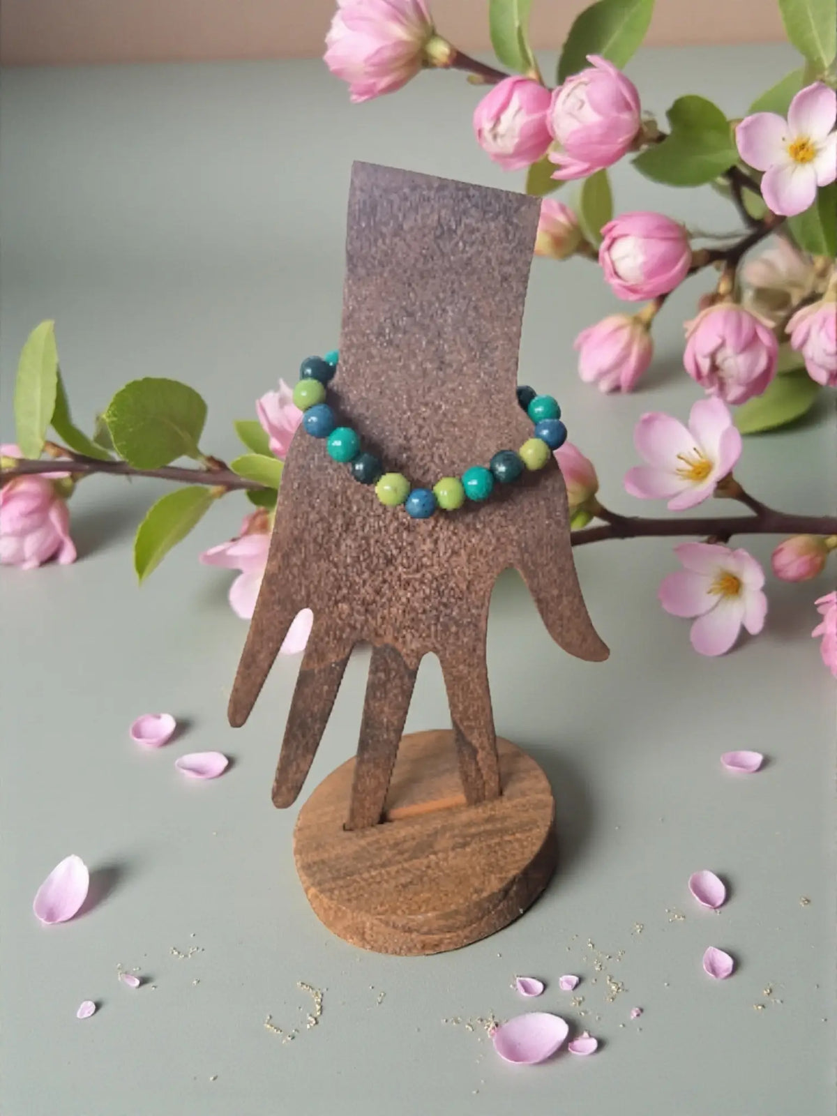Green forest pambil seed bracelet with turquoise and lime green beads displayed on rustic wooden stand fair trade forest seed bracelets