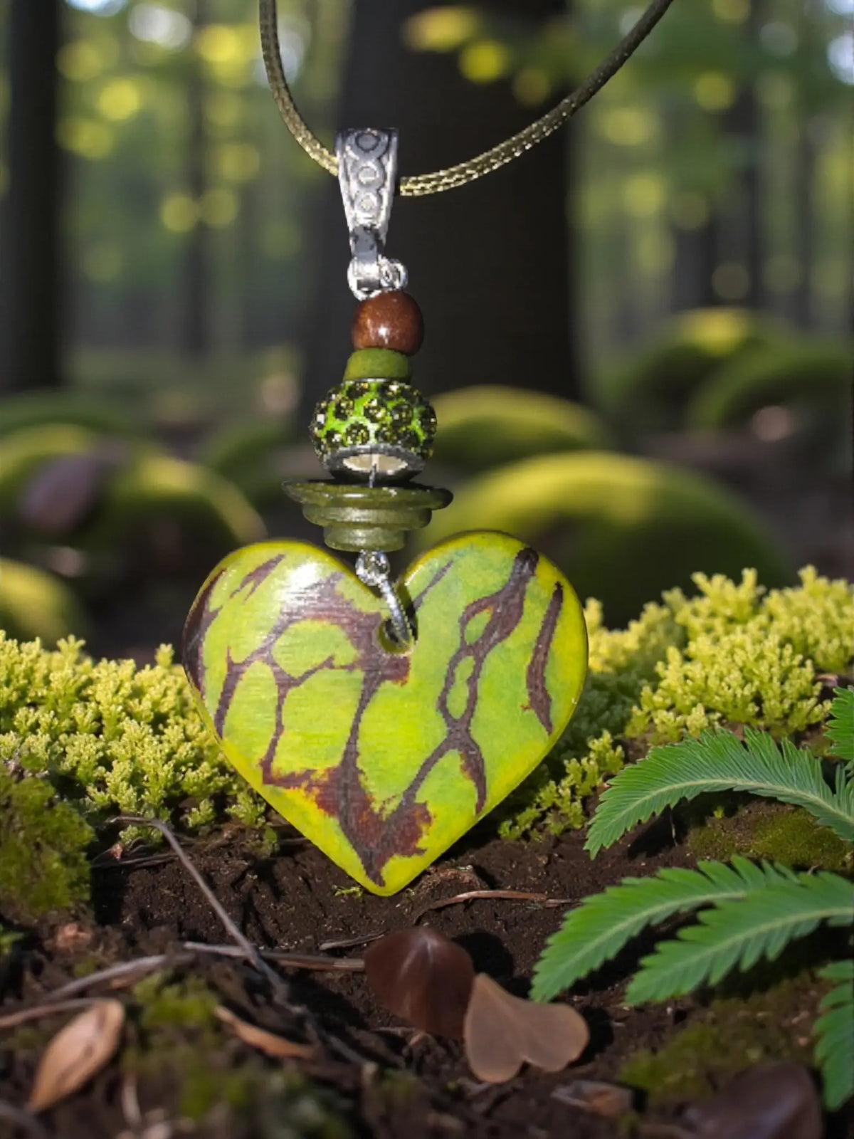 A green rustic carved tagua heart pendant necklace with earthy brown maroon pattern and silver-toned ornate bail and chain