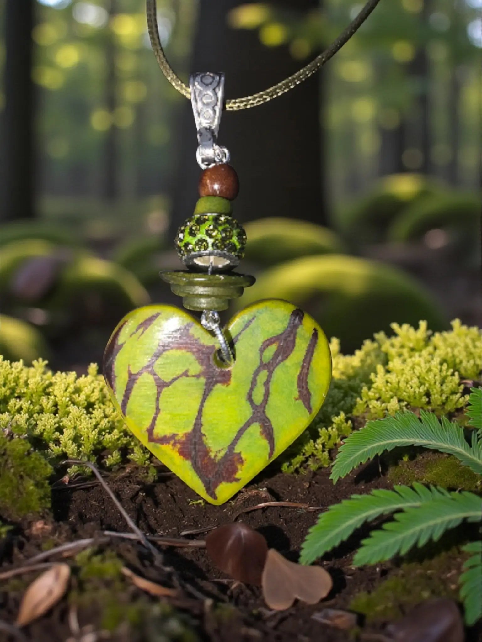 A green rustic carved tagua heart pendant necklace with earthy brown maroon pattern and silver-toned ornate bail and chain