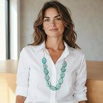 A turquoise hand carved tagua nut yoli necklace multi pendant with a white outline worn with a crisp white blouse