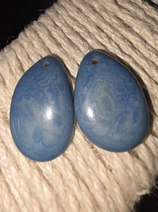 Heather blue tagua grain earrings with blue teardrop stone pendants featuring silver swirl bird designs